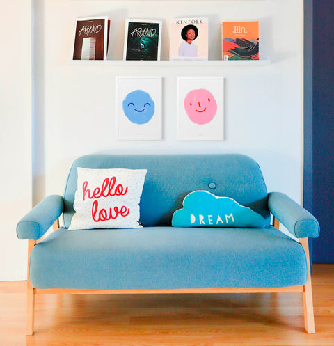 Emotions poster prints with smiling emojis hanging above sofa in modern living room.