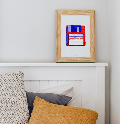 Floppy disk illustration wall art print with the words Good memories hanging above bed in bedroom.