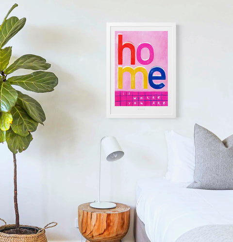 Bold and colorful Typography poster featuring an illustrated phrase saying "home is where your are" with vibrant pink, red and yellow color palette.