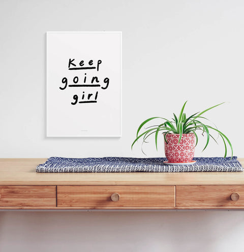 Inspirational wall quotes for women with black and white hand painted phrase saying "keep going girl" and hanging in nordic contemporary interior.