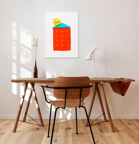 Simple house illustration wall decor with the quote Home. This graphic art print is hanging above a minimalist wooden desk in a modern home office space.