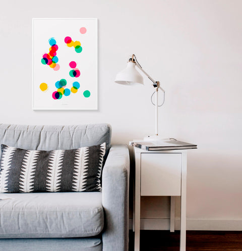 Colorful confetti illustration wall art print hanging above sofa in neutral white living room.