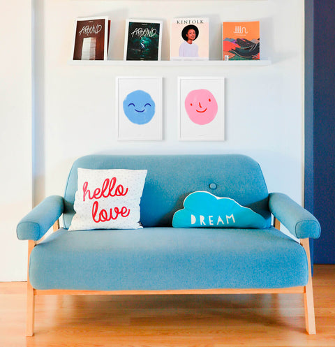 Emotions poster prints with smiling emojis hanging above sofa in modern living room.
