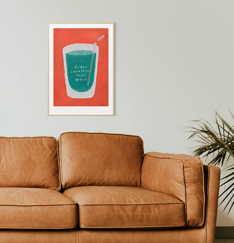 Simple and modern illustration wall art print featuring a glass of green smoothie and the quote "green smoothies taste green" hanging over the sofa in bright living room.