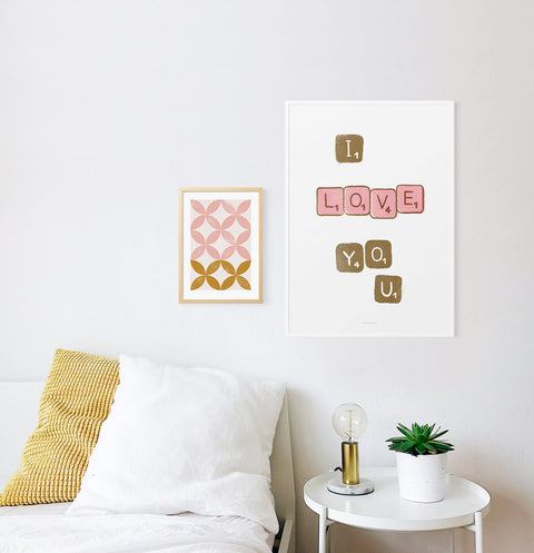 I love you poster about love. Bedroom prints above bed featuring scrabble letters saying the words "I love you". Love poster hanging over the bed in white minimalist bedroom. Bedroom gallery wall.