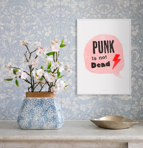 Girl power typography poster featuring a pink speech bubble and hand lettered quote Punk is not dead. This illustration art print is hanging on the wall with trendy wallpaper.