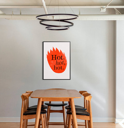 Funky wall art print featuring red flames illustration and hand drawn letters saying Hot, hot, hot. This graphic illustration poster is hanging above a wooden table in a modern industrial dining room