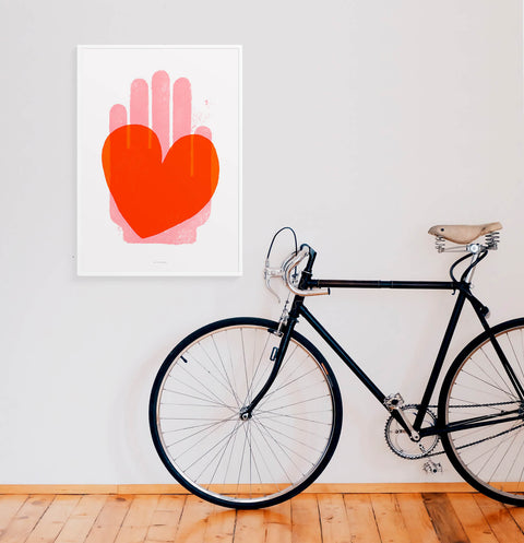 Red heart poster art print in modern minimalist living room. Illustration print hanging on a white wall with a hipster bicycle. Trendy posters for bedroom and minimalist living room prints.