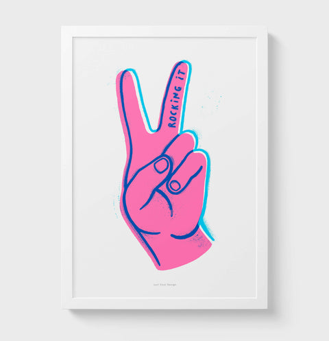 Graphic illustration wall art with bold colors featuring a hand making the victory sign with the fingers. Hand written quote saying "Rocking it"