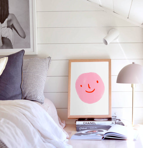 Pink smiley face poster in white scandinavian bedroom.