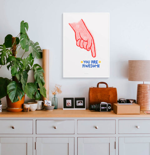 Quote print with a finger pointing the words You are awesome hanging in scandinavian living room.